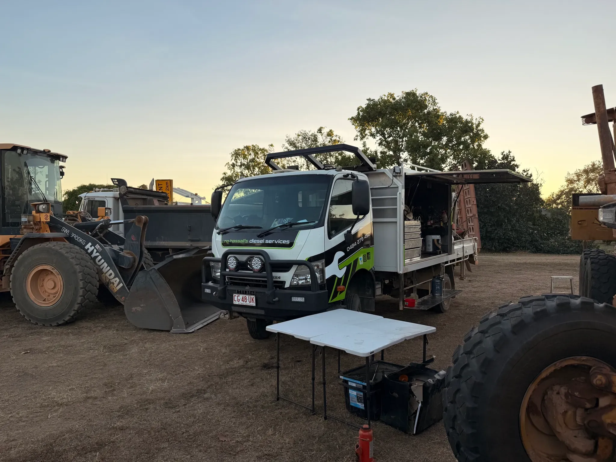 NHDS service truck set up on site beside a wheel loader at first light