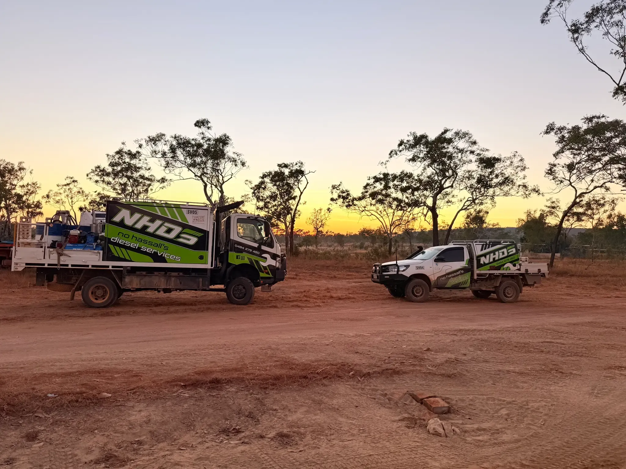 NHDS service truck and ute parked on red dirt at sunset out in the Territory