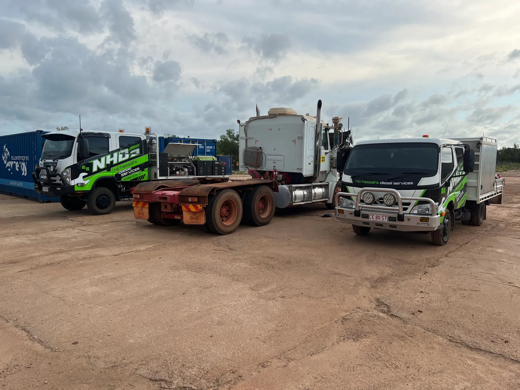 Two NHDS service trucks attending a prime mover on a red dirt yard